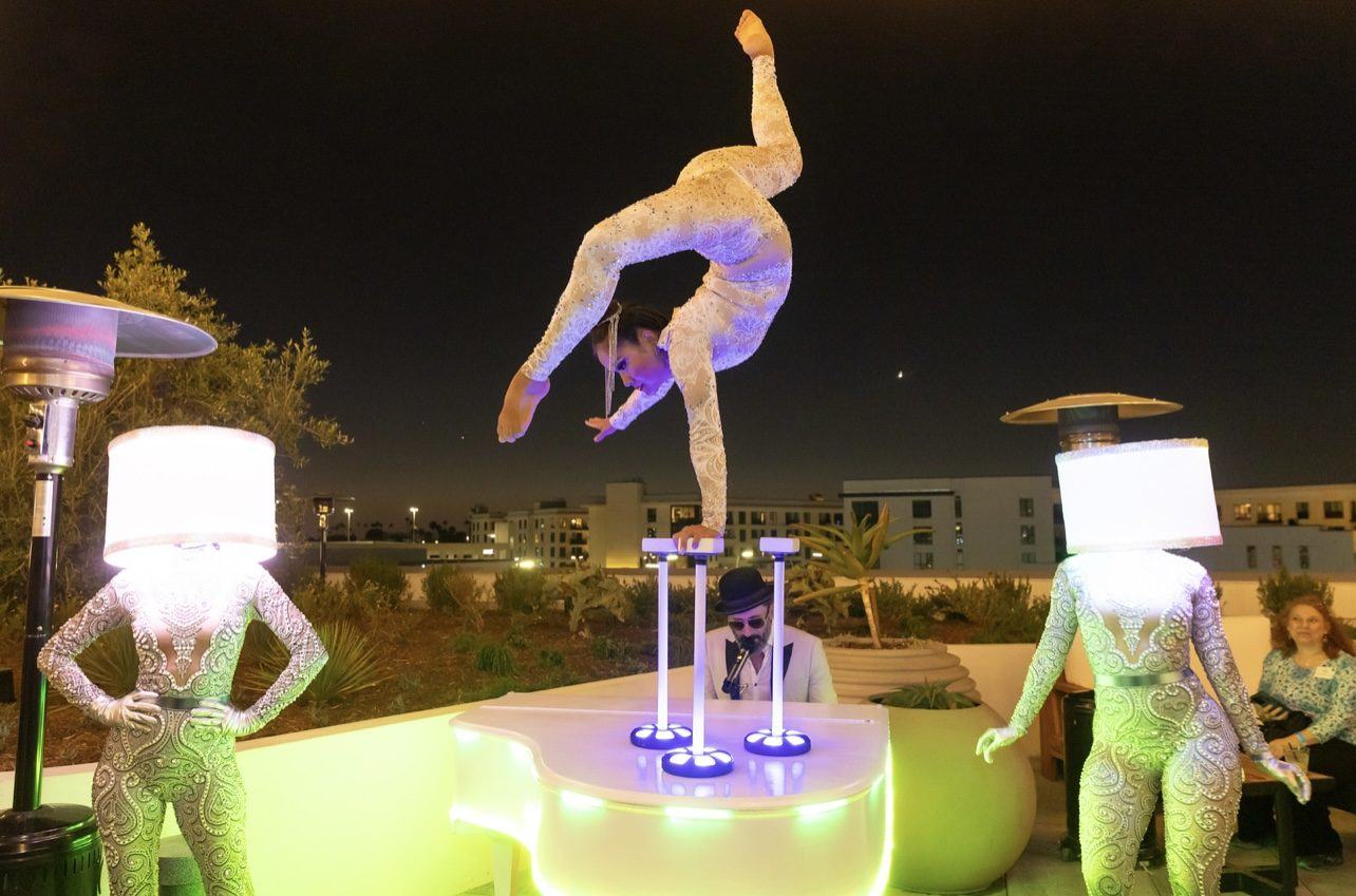 Aerial performer at a night event with illuminated cocktail tables