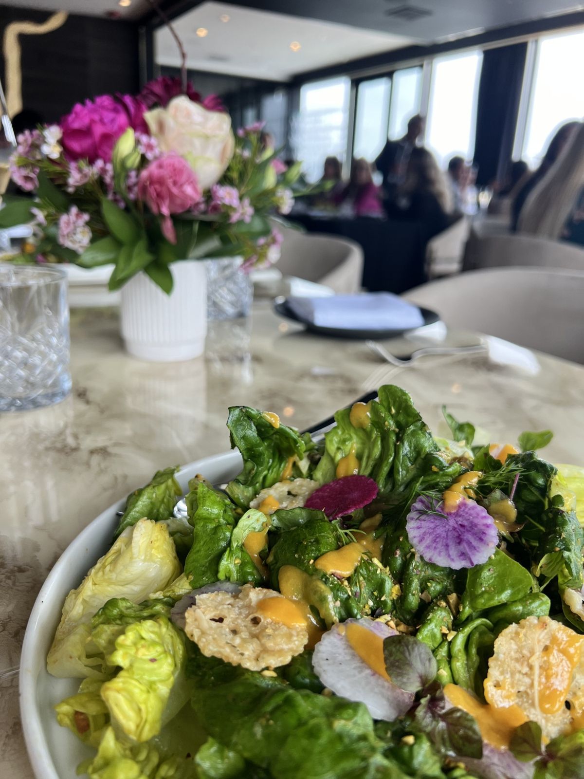 Plated salad course with edible flowers, ready to serve